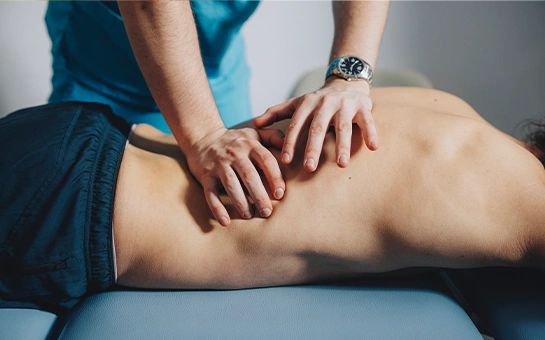 Hands of a practitioner applying pressure along a person’s bare back